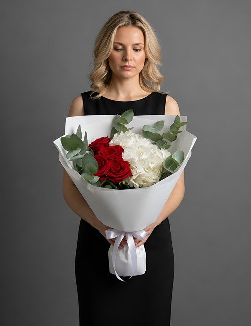 A high-contrast 'Morning Glow' bouquet featuring deep red Naomi roses and large, voluminous white hydrangea clusters accented with aromatic silver-green eucalyptus.