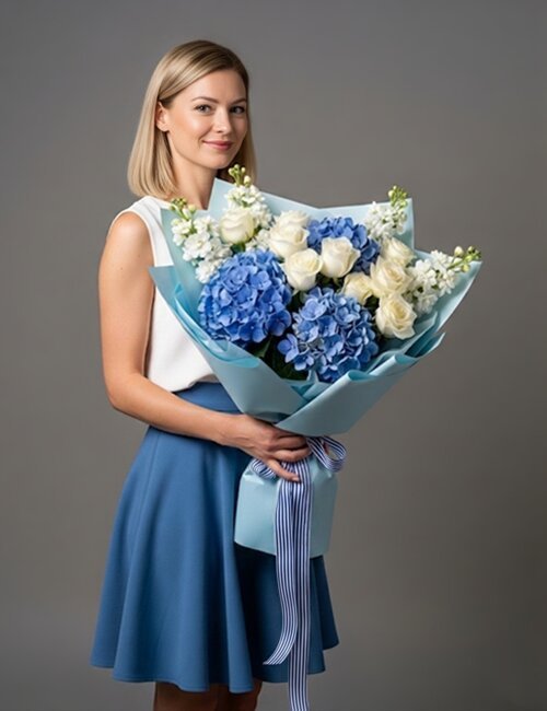 The "Bundle of Joy" bouquet pictured here features blue hydrangeas, white matthiola, and Avalanche roses.